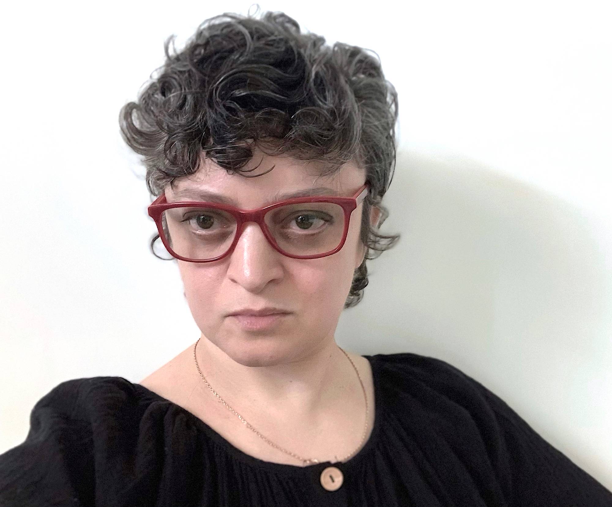 Image of Katya Grokhovky wearing red glasses & black shirt.